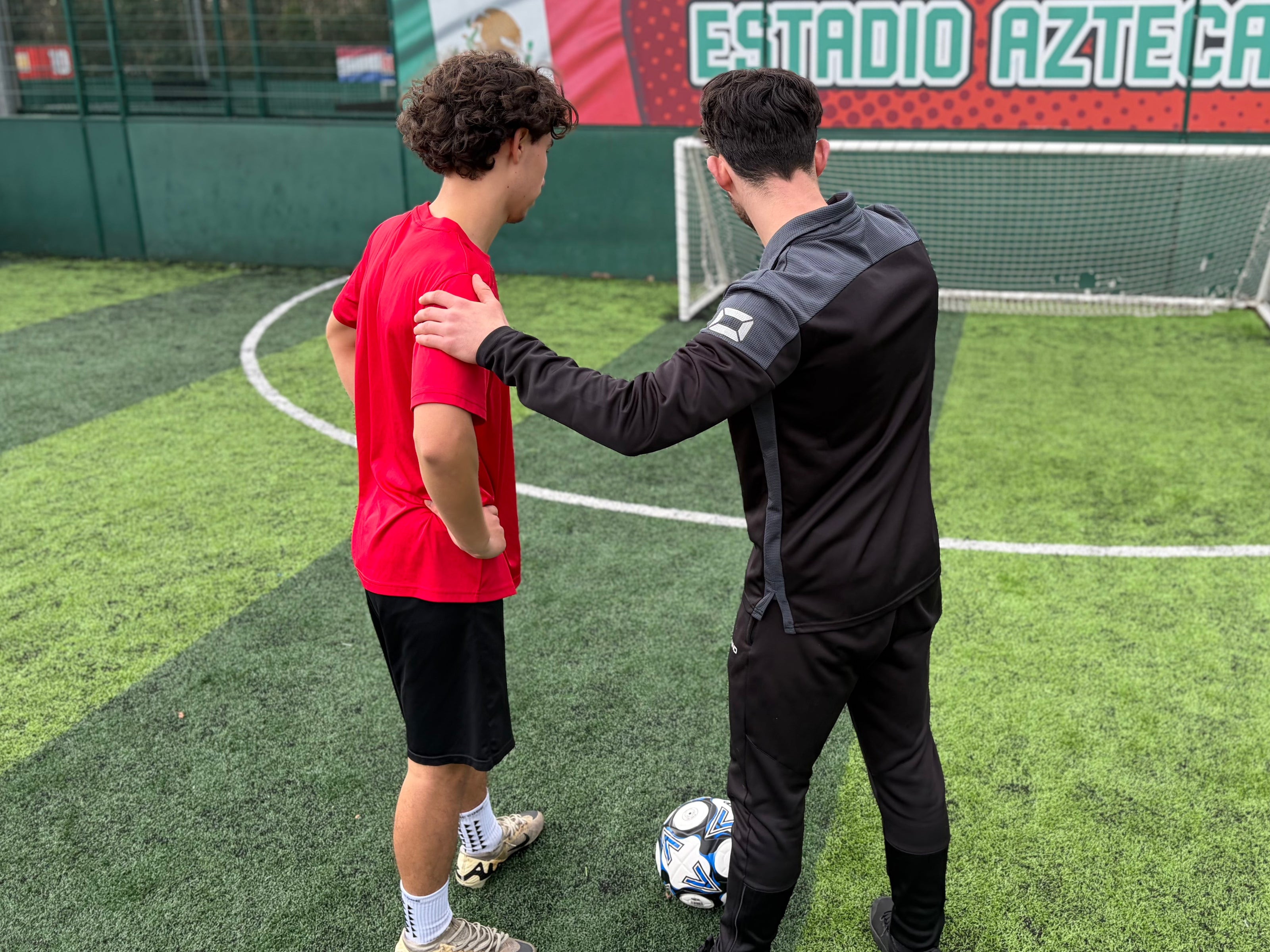 Technical football coach demonstrating drills and helping the football player understand positioning.